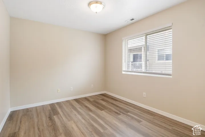 Room featuring wood-finish flooring, neutral wall paint, and a window with horizontal blinds