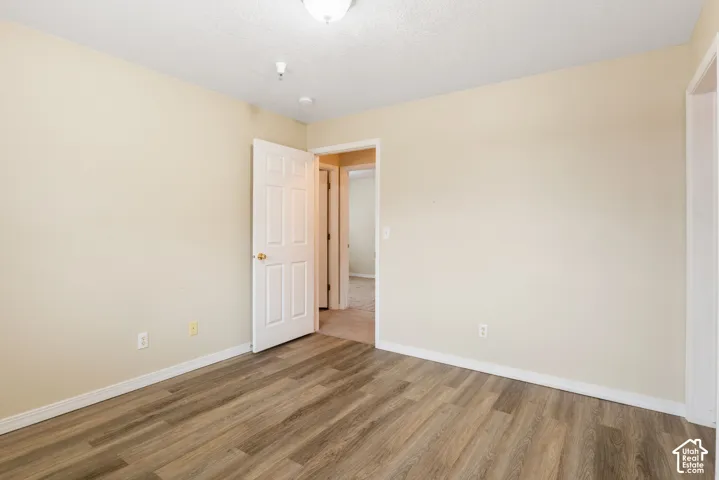 Room featuring wood-finish flooring, neutral wall paint, and a six-panel interior door