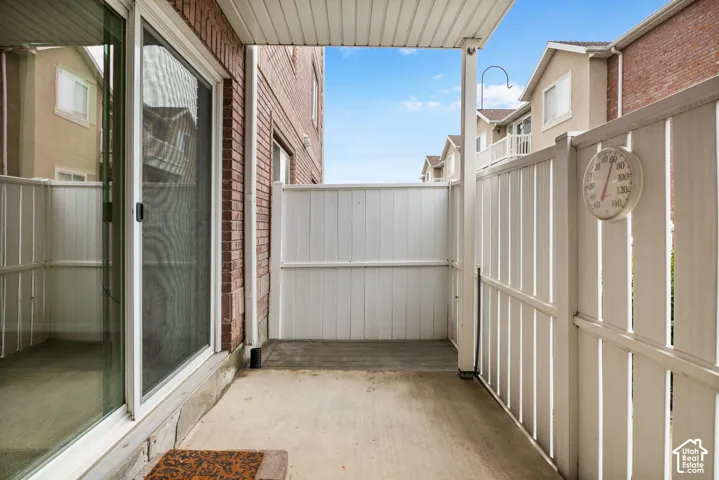 Covered concrete patio featuring white vinyl privacy fencing and a sliding glass door entry