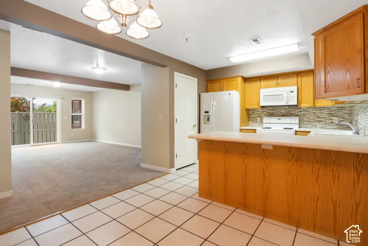 Kitchen featuring wood cabinetry, solid-surface countertops, tile flooring, and a multi-toned stone tile backsplash