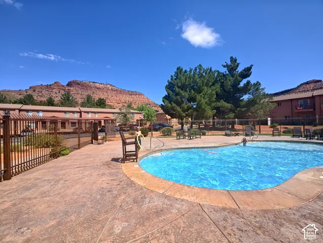 Swimming pool area featuring textured concrete decking, metal perimeter fencing, and red rock mountain scenery