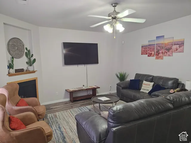 Fireplace with a wooden mantel, built-in wall niche, ceiling fan with integrated lighting, and wood-finish flooring