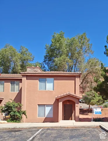 Exterior featuring stucco siding, stone chimney masonry, tiled roof detailing, and a covered entry
