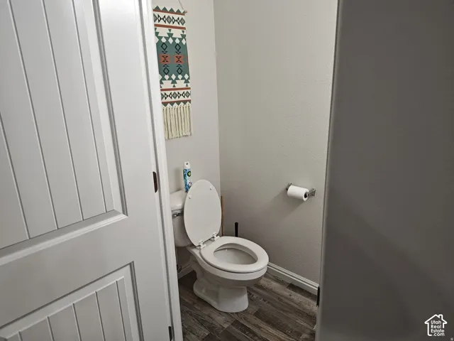 Paneled interior door, wood-finish flooring, and wall-mounted metallic toilet paper holder