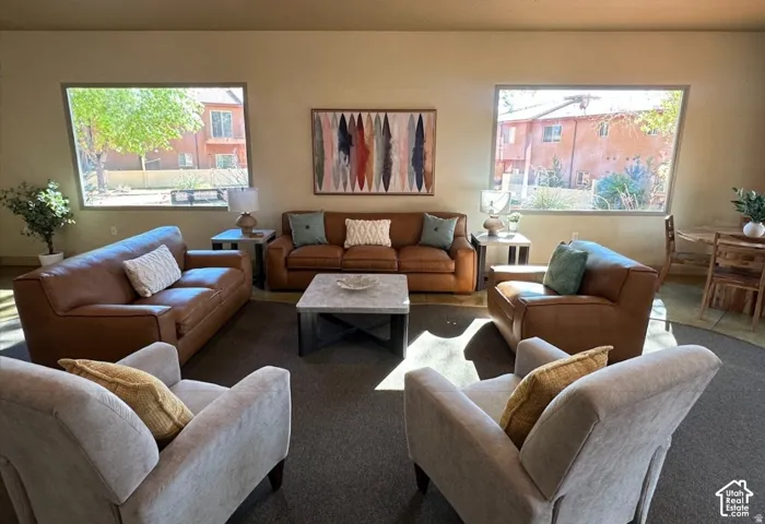 Spacious living area featuring neutral wall tones, carpeted flooring, and two expansive picture windows