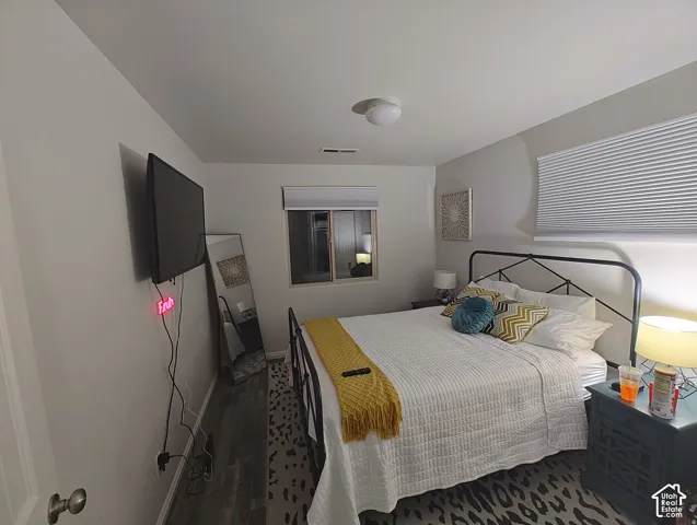Neutral-toned bedroom featuring wood-finish flooring and light-filtering cellular shades