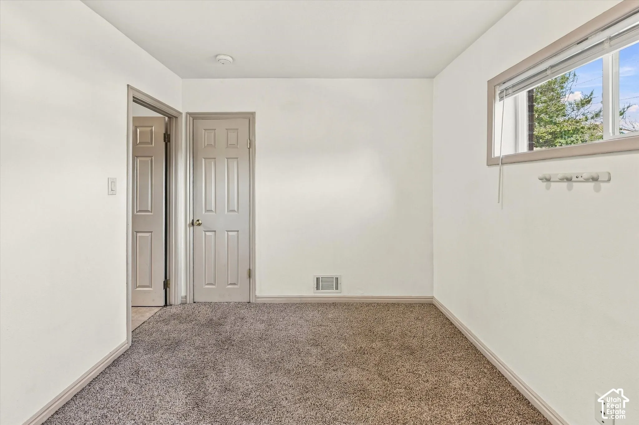 Neutral-toned carpeting, two interior doors, and a rectangular window with a horizontal slider