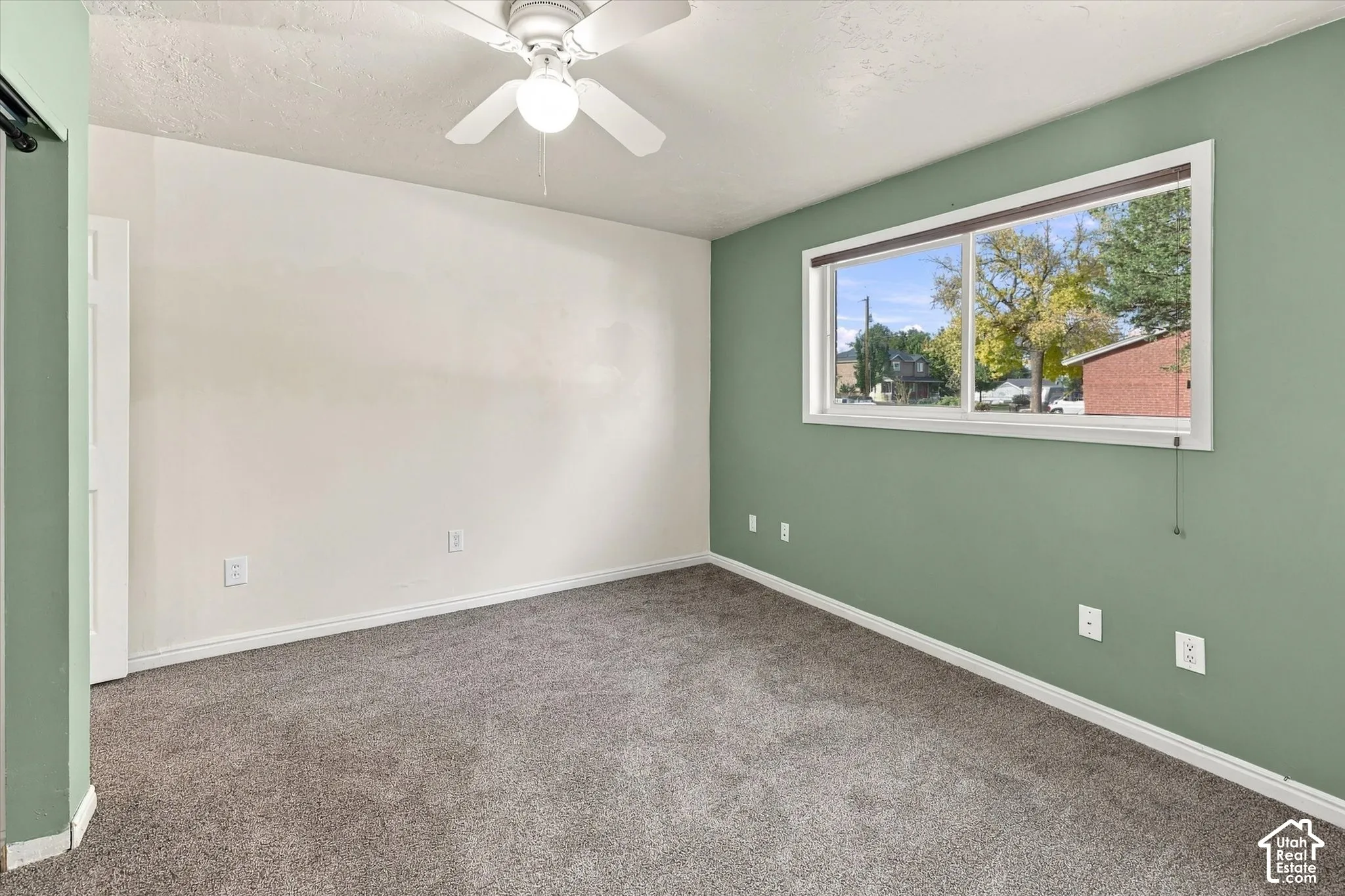 Neutral-toned carpeting, ceiling fan with integrated light fixture, and sliding glass window