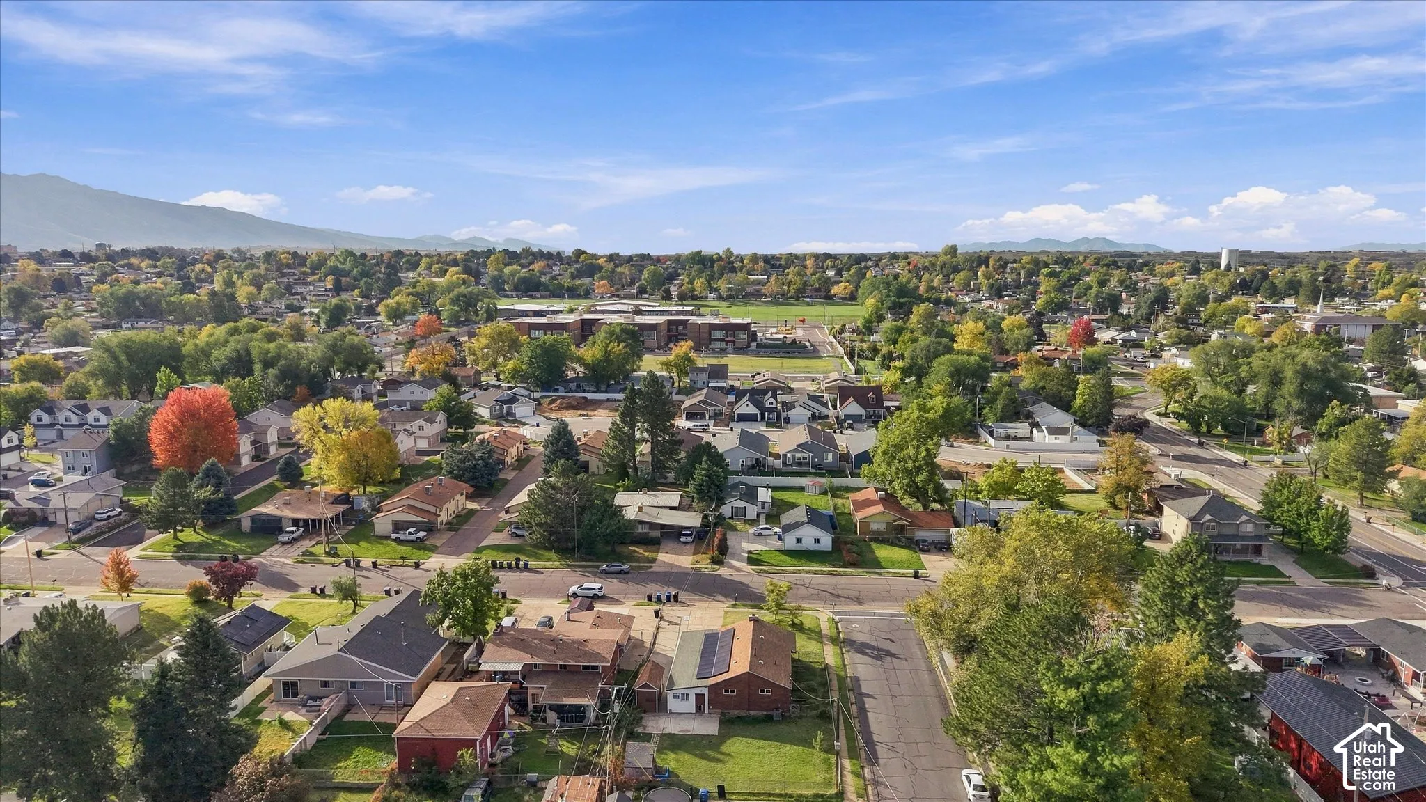 Aerial perspective of the residential area featuring mature trees, expansive landscaping, and prominent mountain backdrops