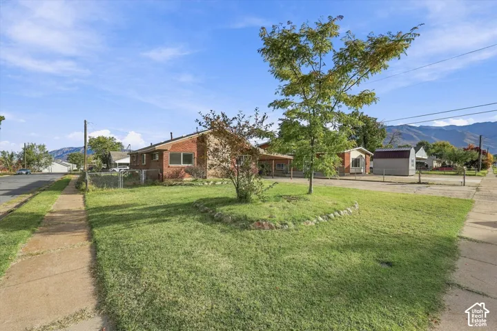 Brick exterior, attached carport, detached storage structure, concrete driveway, and rock-lined landscaping