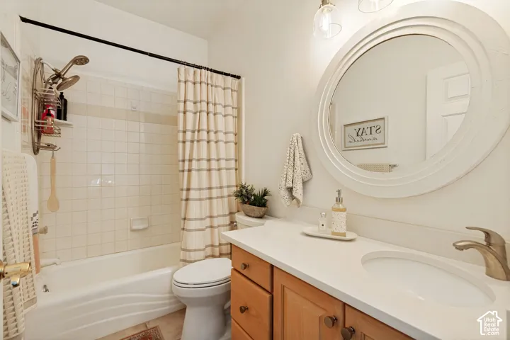 Bathroom featuring a vanity with wood cabinetry, a light-toned countertop, an integrated sink, and an oval mirror, complemented by a bathtub with tiled surround and overhead shower fixture