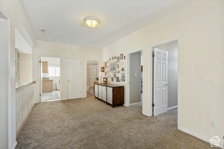 Neutral carpeting, white interior doors, and a wood-finish bannister featuring vertical balusters
