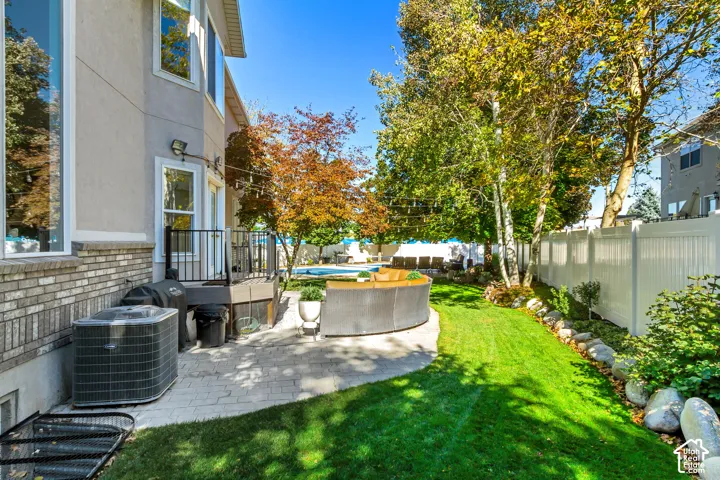 Backyard featuring paver stone patio, swimming pool, manicured lawn, mature trees, and privacy fencing