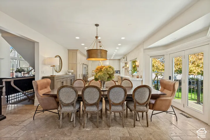 Open-concept dining area featuring stone tile flooring, a large drum pendant light fixture, recessed lighting, and double glass doors providing external access