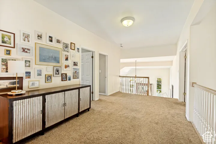 Open landing area featuring neutral carpeting, a built-in storage console, and a white wood-spindle banister