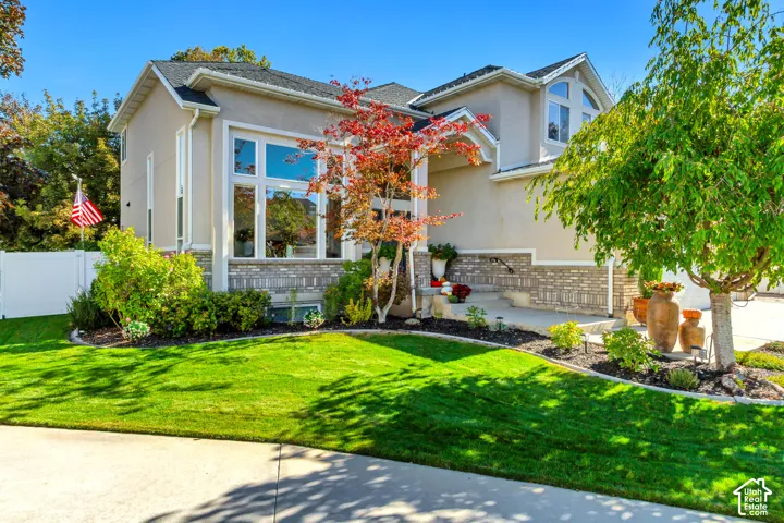 Exterior featuring stucco and brick masonry, large multi-pane windows, arched transom window, and concrete walkway