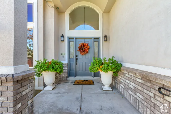 Covered entryway featuring a double door entrance, arched transom window, brick masonry accents, and wall-mounted exterior lighting