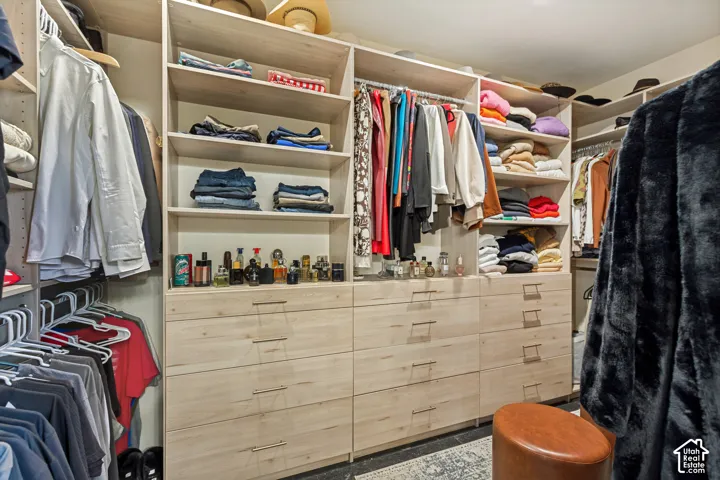 Walk-in closet featuring light wood-finish custom cabinetry, floor-to-ceiling adjustable shelving, integrated drawer storage, and metal hardware