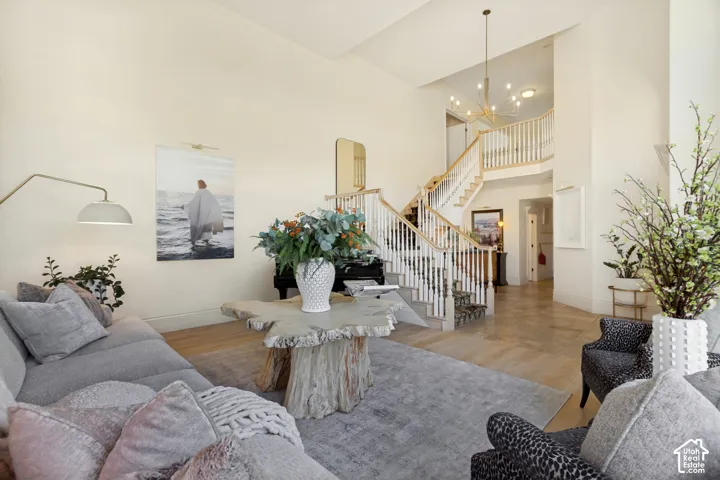 Two-story foyer featuring high ceilings, wood-finish flooring, a staircase with decorative railings, and a multi-arm chandelier