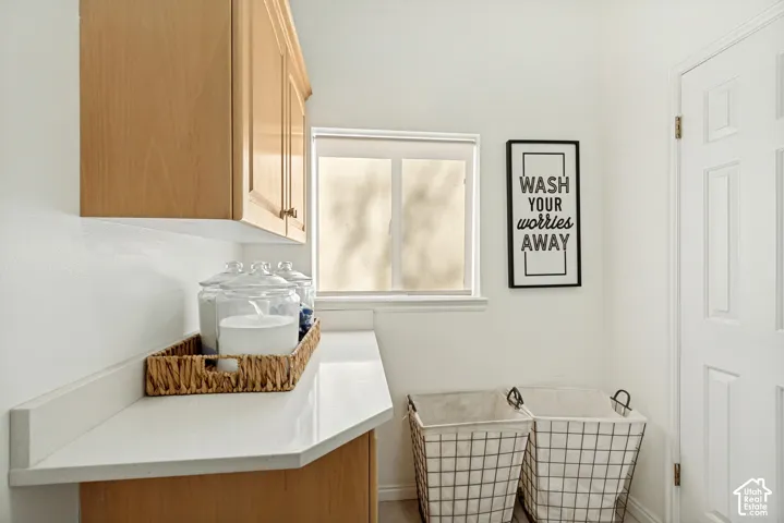 Light-wood cabinetry, white countertop, white backsplash, sliding window, and a white six-panel door