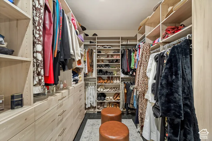 Custom walk-in closet featuring floor-to-ceiling light-toned wood cabinetry, built-in shelving, integrated hanging rods, and integrated soft-close drawers with metallic pulls