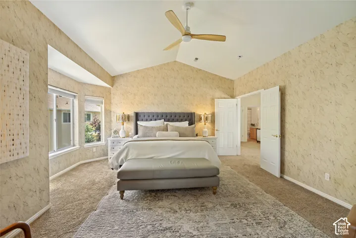 Vaulted ceilings, carpeted flooring, textured wallpaper, multi-panel doors, and a three-blade ceiling fan