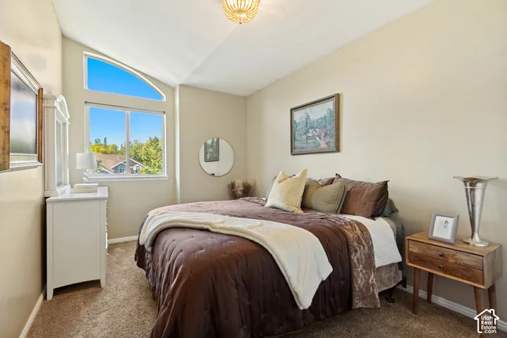 Vaulted ceilings featuring a supplemental arched window, neutral wall paint, and wall-to-wall carpeting