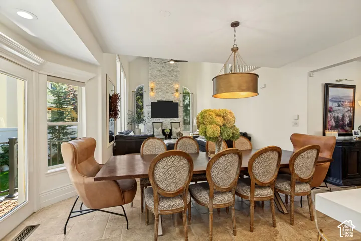 Open floor plan featuring tile flooring, a multi-story stone-finish fireplace, and a drum-style pendant light fixture