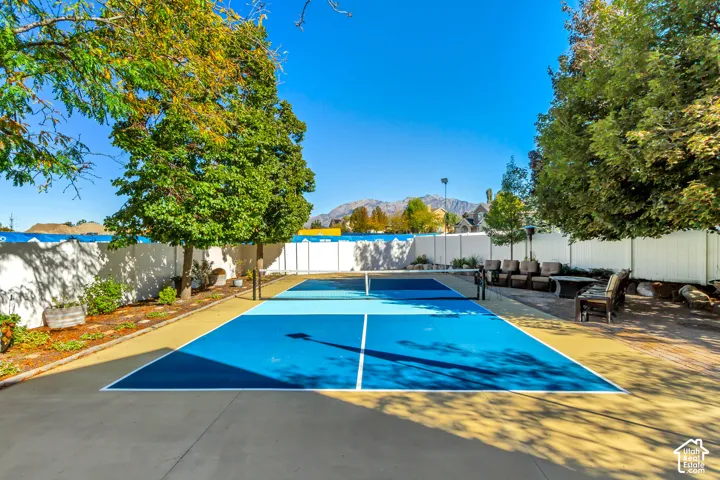 Private court featuring a two-toned sports surface and a perimeter vinyl fence with mountain scenery
