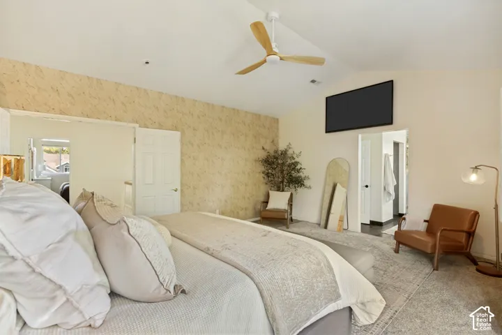 Vaulted ceiling featuring a three-blade wooden ceiling fan and neutral wall-to-wall carpeting
