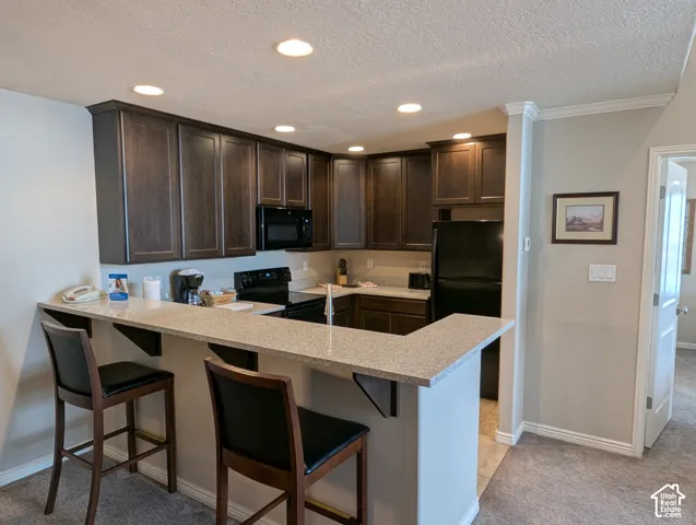 Kitchen featuring dark wood cabinetry, bar, and black built-in appliances