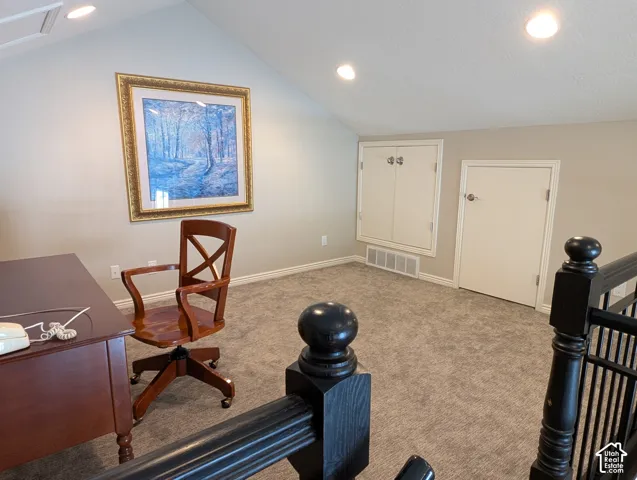 Upstairs loft space with vaulted ceilings, recessed lighting, neutral carpeting, and built-in under-eave storage access