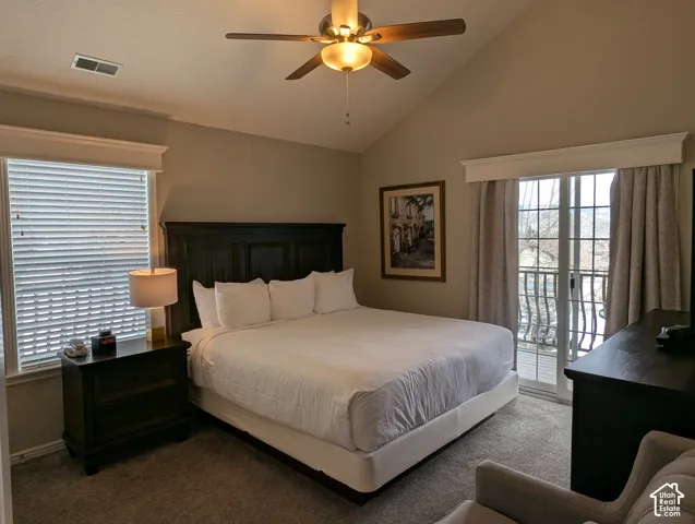 Primary bedroom with vaulted ceiling, ceiling fan with integrated lighting, wall-to-wall carpeting, and sliding glass door with external balcony access