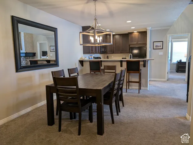 Dining area featuring a pendant light fixture, wall-mounted mirror, kitchen with dark-finish cabinetry, bar, and recessed lighting