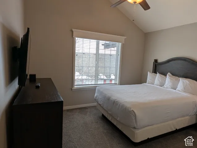 2nd bedroom with vaulted ceiling, neutral wall tones, carpeted flooring, window with a valance, and a ceiling fan
