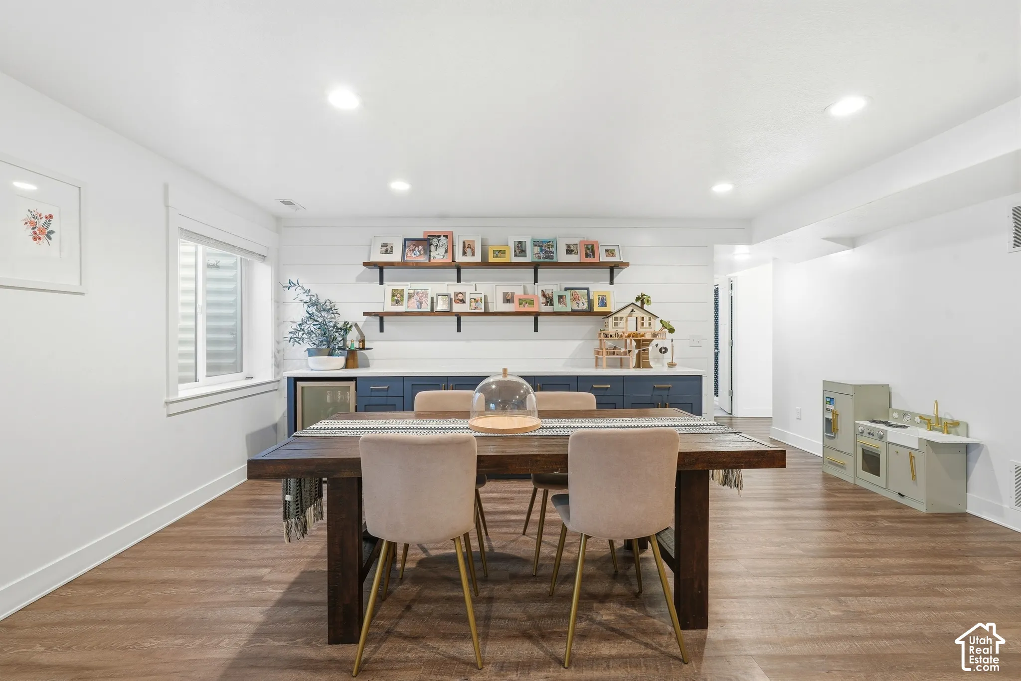 Wood-finish flooring, shiplap wall treatment, built-in cabinetry with integrated beverage refrigerator, and open wall-mounted shelving