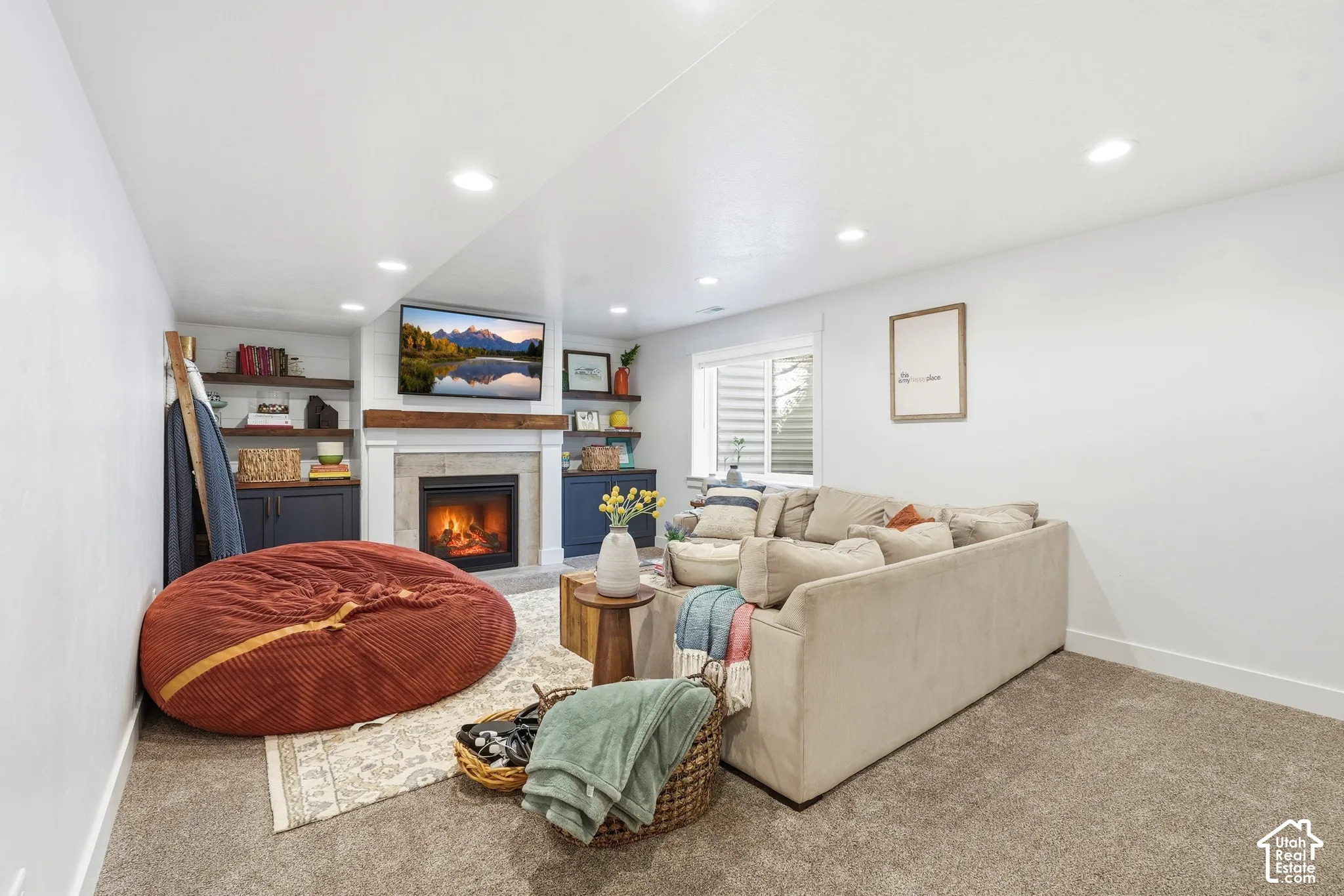 Fireplace with a natural wood mantel, recessed lighting, built-in cabinetry, and open shelving