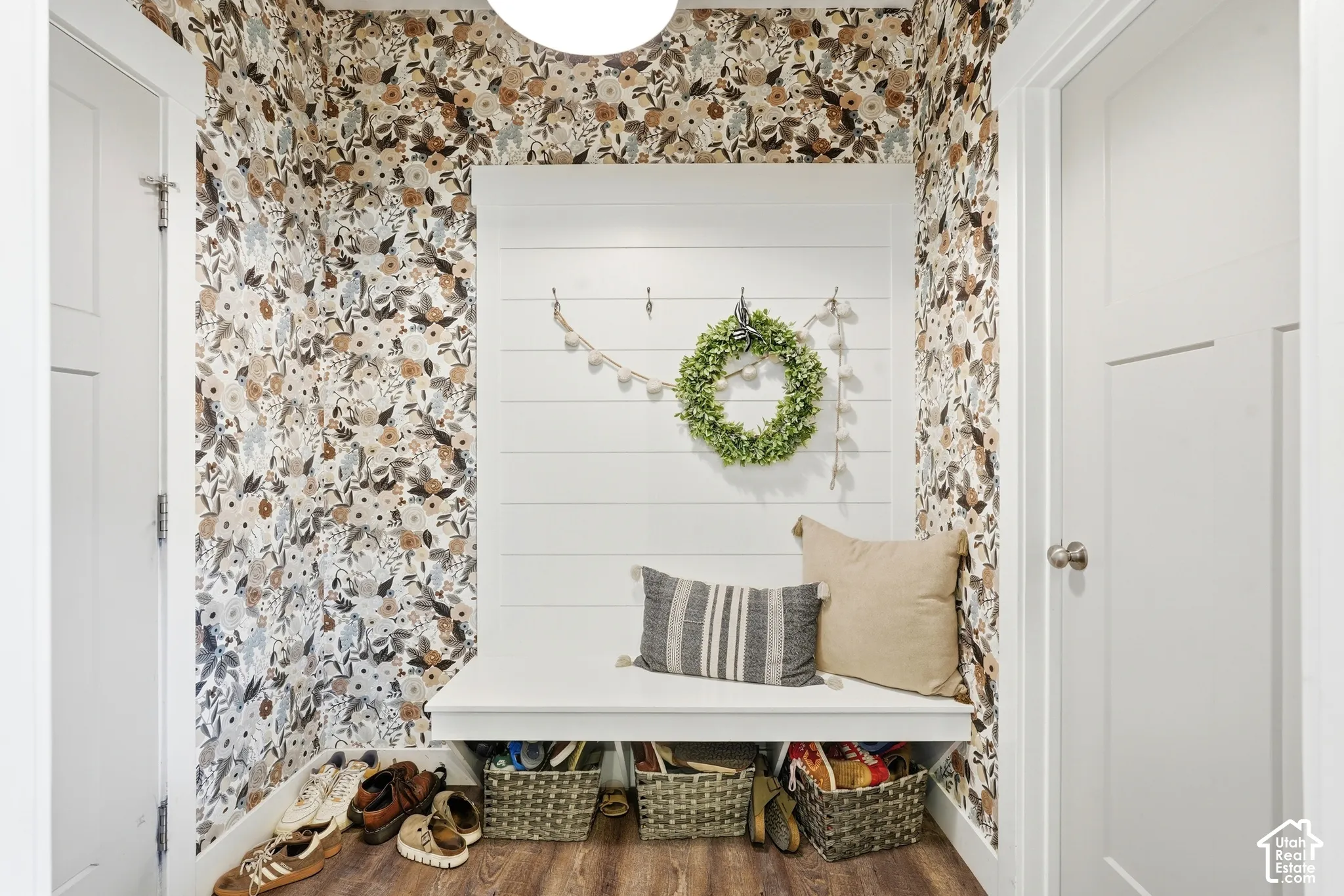 Built-in bench with white shiplap wall paneling, patterned wall covering, wood-finish flooring, and shaker-style doors