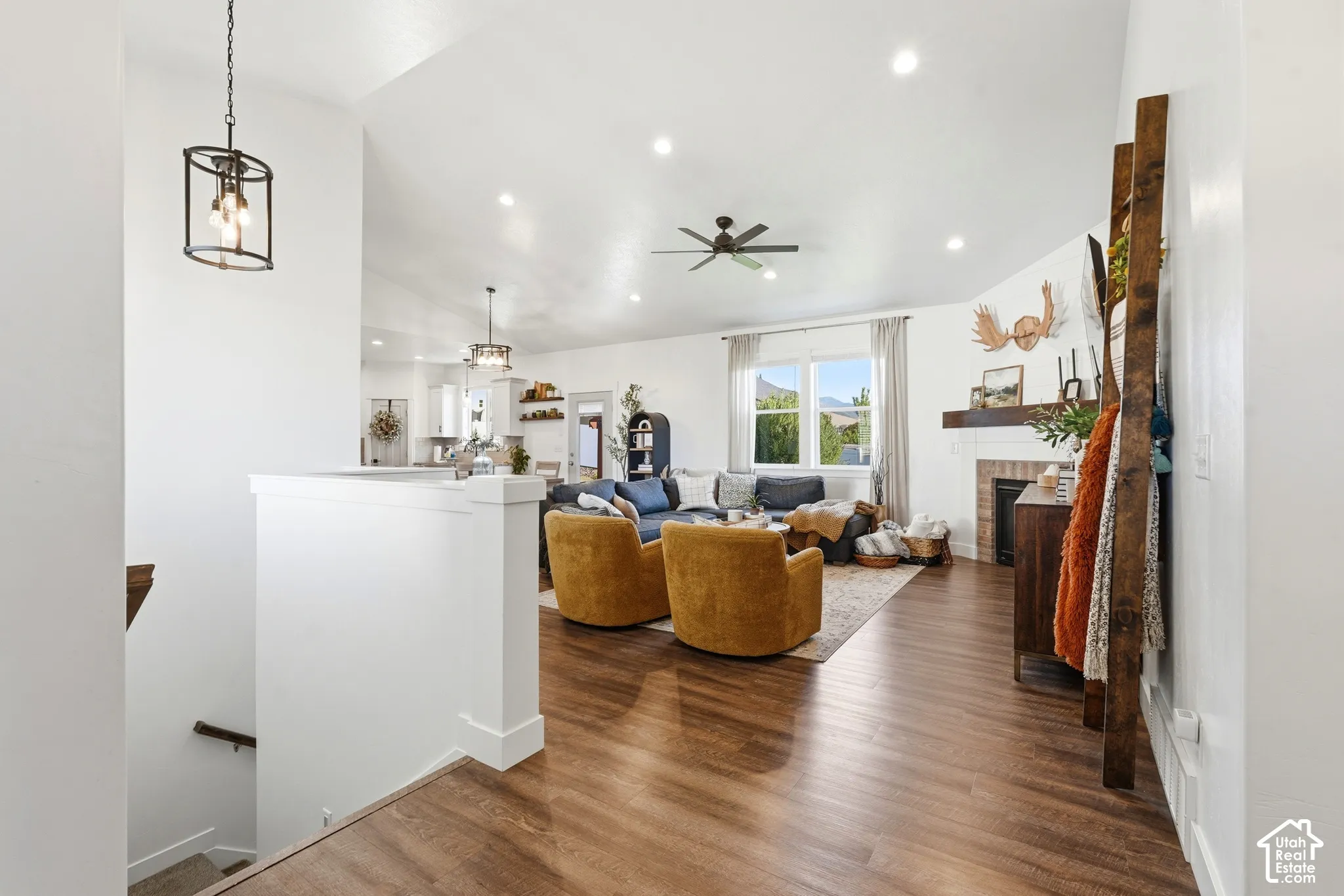 Open-concept interior featuring wood-finish flooring, vaulted ceilings, recessed lighting, and a fireplace with a wood mantel