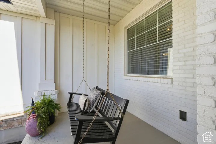 Covered front porch featuring white painted brick masonry, vertical board siding, and a concrete floor