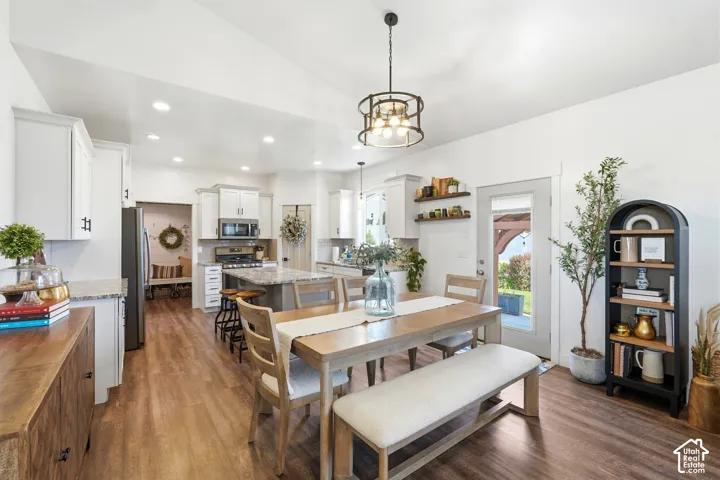 Kitchen featuring white cabinetry, stone-finish countertops, wood-finish flooring, a metal drum pendant light, and built-in floating shelving
