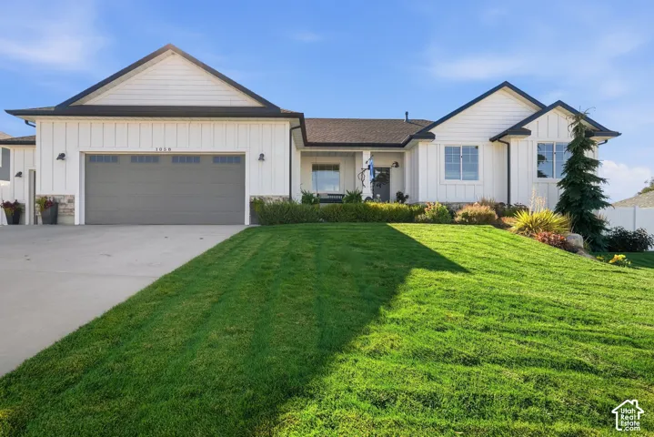 Modern farmhouse exterior featuring vertical board-and-batten siding, stone veneer accents, an attached multi-car garage, and manicured landscaping