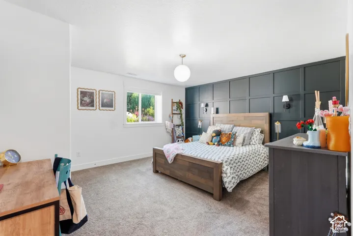 Interior space featuring dark-toned wood paneling, wall-mounted light fixtures, a globe pendant light, and neutral carpeting