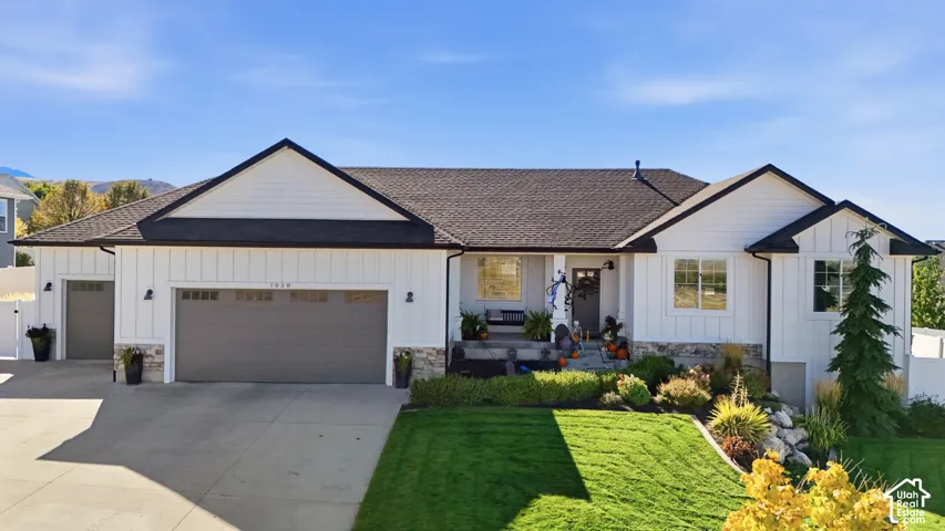 Board-and-batten siding exterior featuring stone veneer accents, multi-gabled roofline, three-car garage, and covered entryway