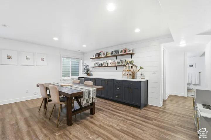 Shiplap wall detailing, built-in dark cabinetry with light-toned countertops, recessed ceiling lighting, and wood-finish flooring