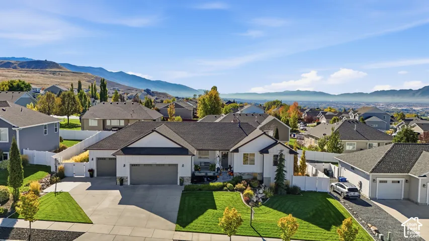 Single-story residence featuring a multi-car garage, white siding, stone veneer accents, architectural roof shingles, and landscaped lawn