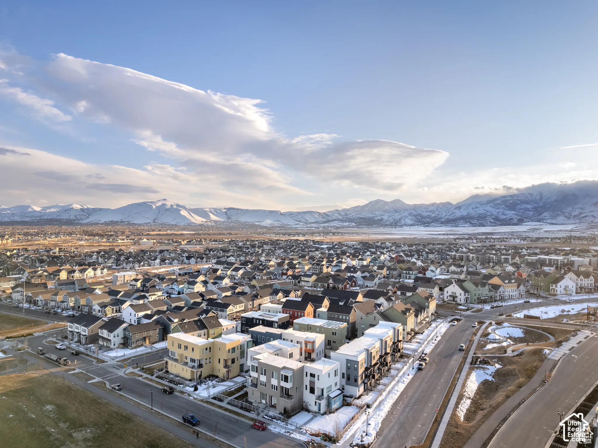 Aerial perspective of a multi-level residential development featuring contemporary architectural design, expansive mountain backdrops, and paved roadway access