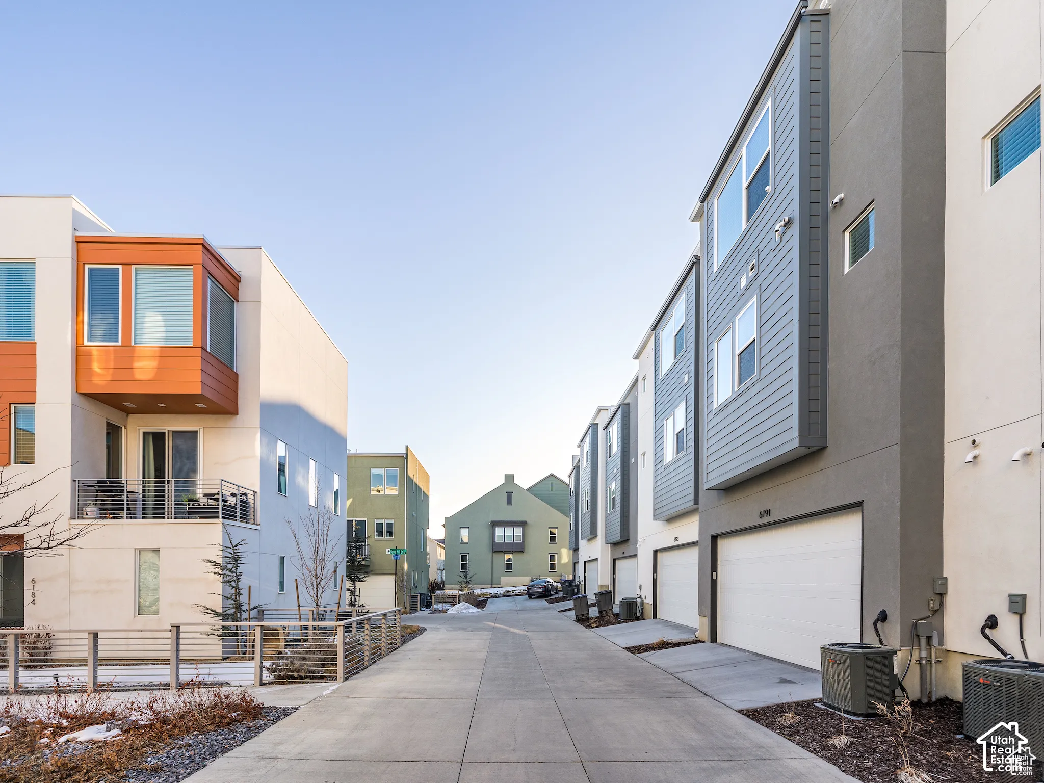 Contemporary multi-level exterior featuring smooth stucco and horizontal siding, private balcony with cable railing, and attached garage doors
