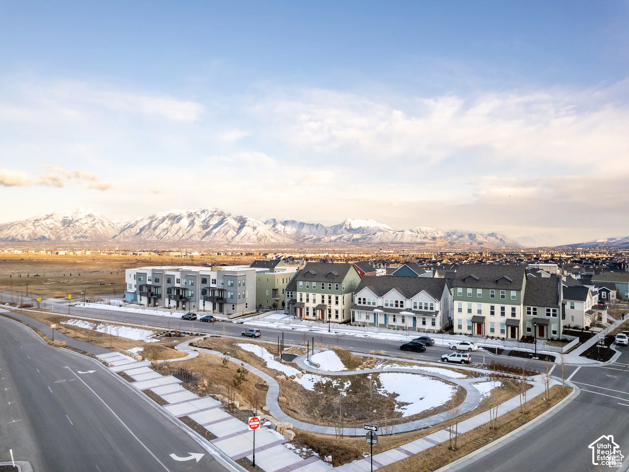 Multi-family residential community featuring multi-story exteriors with varied facades and gable rooflines, situated with a prominent snow-capped mountain backdrop