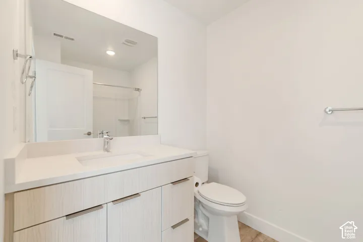 Bathroom featuring a light-toned wood-finish vanity, integrated countertop with rectangular basin, large wall-mounted mirror, and chrome finish hardware